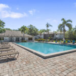 Larger rectangular pool with cobblestone deck and pool chairs