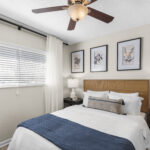Bedroom with ceiling fan and blinds and curtains over the window