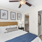 Bedroom with ceiling fan, and walk in closet, with a view of a bathroom just outside the door