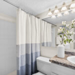 Bathroom with granite counter top, orchid in a vase, blue linens